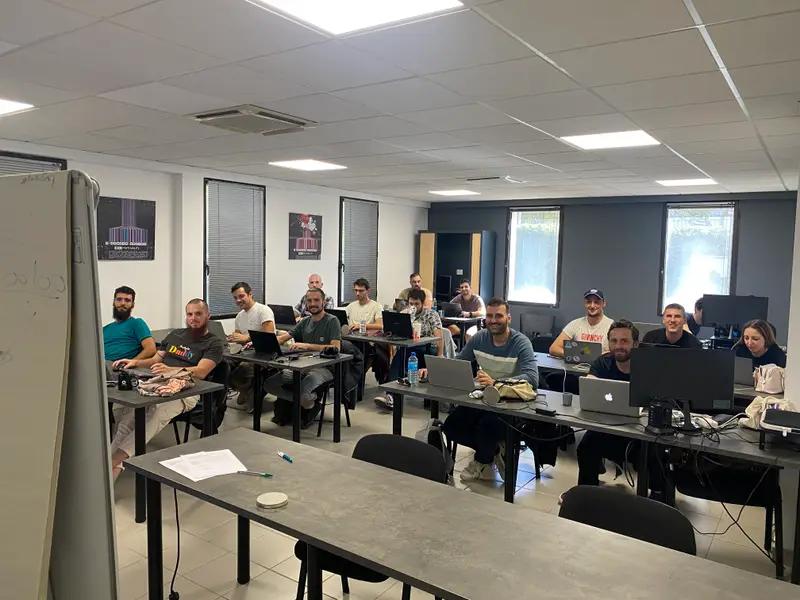 Une promotion en cours dans la salle de formation, ordinateurs ouverts