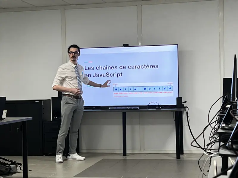 Un formateur devant l’écran affichant « Les chaînes de caractères en JavaScript »