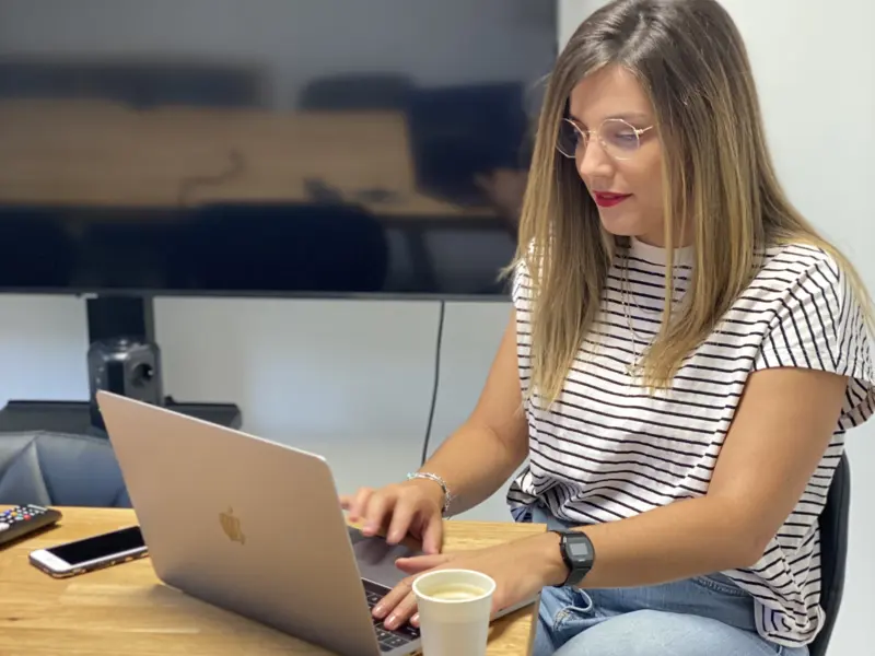 Une élève concentrée sur son ordinateur portable, un café à côté