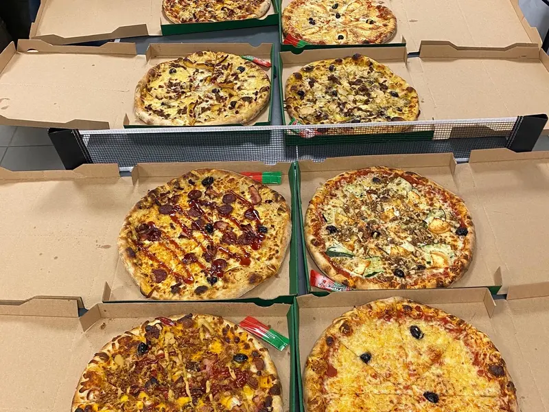 Six pizzas dans leurs cartons, ouverts sur une table