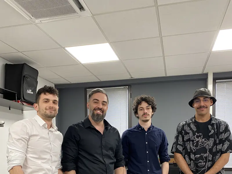 Quatre élèves en tenue de circonstance, debout dans la salle de l’école